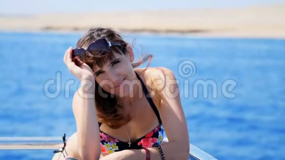 夏天大海肖像美丽的年轻黑发女人穿着泳衣和太阳镜站在甲板上视频的预览图