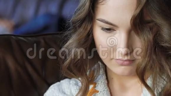 在皮革沙发上用手机放松一下美丽的女孩视频的预览图