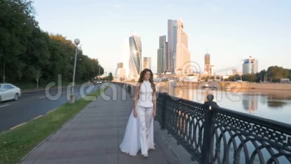 一个留着白发的漂亮女孩正沿着城市的堤岸走着视频的预览图