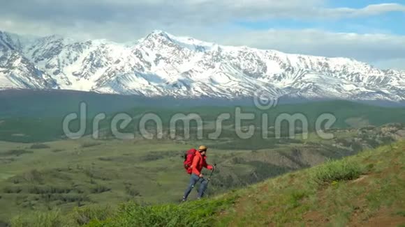 那个带着红色背包的旅行者的女人站在山上看着雪山视频的预览图