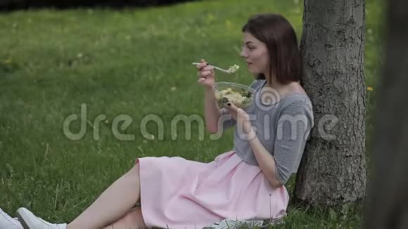 坐在夏日公园里吃新鲜沙拉的女人视频的预览图