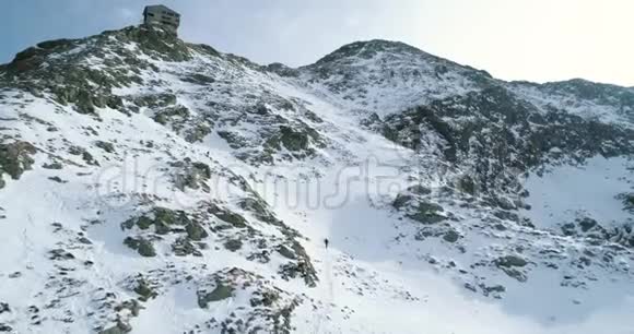在冬天的雪山上向前飞登山滑雪者走上登山雪覆盖了群山视频的预览图