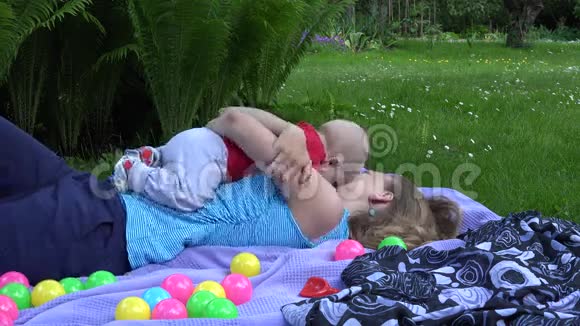 妈妈爱抚小孩子一起在花园里户外玩耍4K视频的预览图