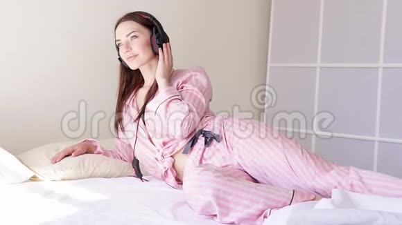 床上穿着睡衣的女人从耳机里随着音乐起舞视频的预览图