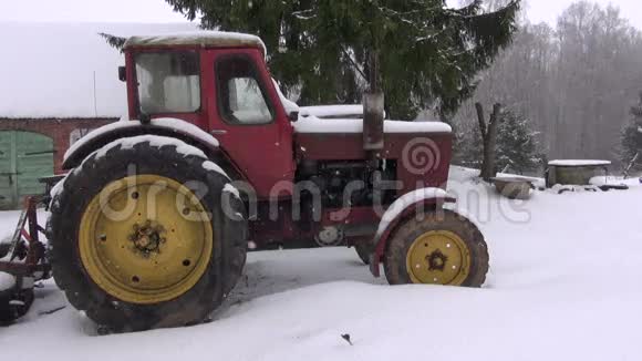 在雪和降雪的农场里的老式复造型拖拉机视频的预览图