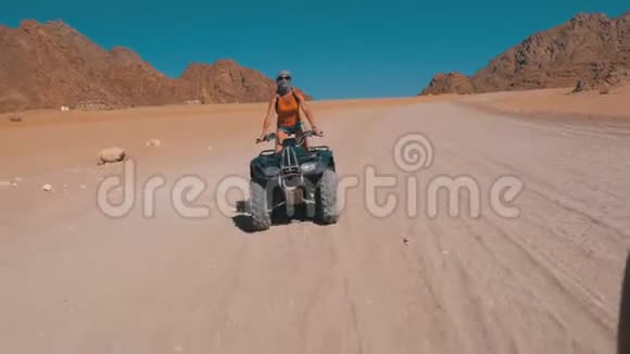 骑着四人自行车的女孩骑着自行车穿越埃及沙漠以山脉为背景视频的预览图