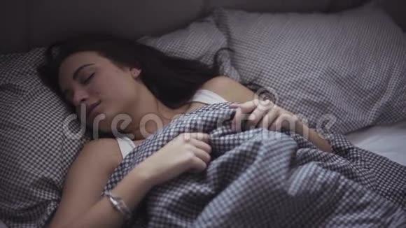慢镜头的一个迷人的白种人女孩谁很容易醒来在她舒适的床视频的预览图
