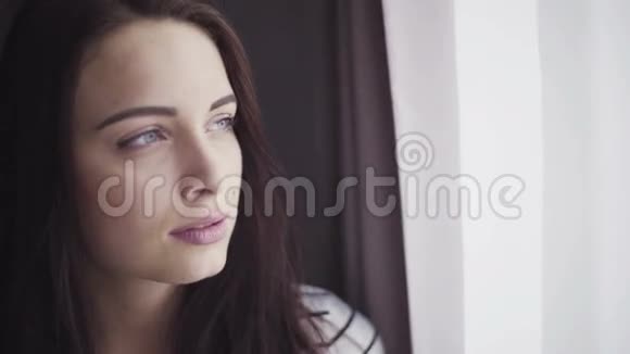 20多岁女性的特写镜头看着窗户然后把她的目光变成照相机视频的预览图