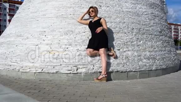 时尚时尚的年轻女模特戴着太阳镜穿着一件黑色连衣裙在户外视频的预览图