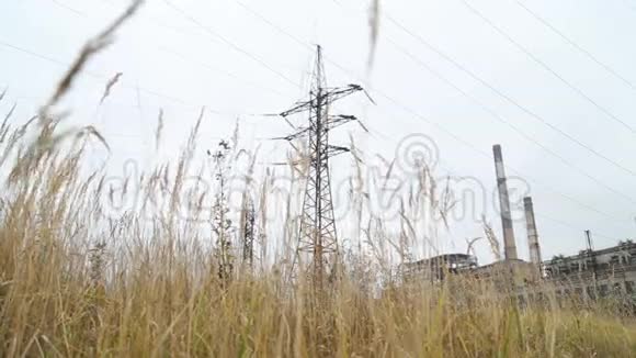 火力发电厂高压线路的旧脏电源前景干涸的高草视频的预览图