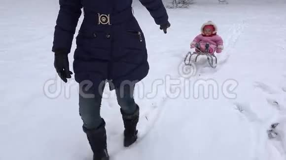 在冬天的度假胜地母亲把女儿抱在雪橇上手持的4K视频的预览图