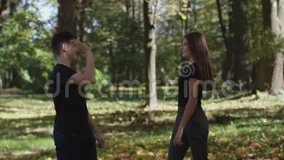 男孩和女孩女士在公园里跳和扔干树叶视频的预览图