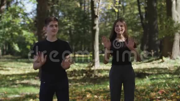 男孩和女孩女士在公园里跳和扔干树叶视频的预览图