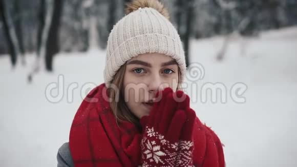 年轻漂亮的女孩穿着暖和的衣服走在圣诞树附近看着摄像机视频的预览图
