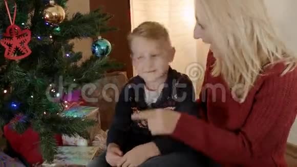 快乐的金发母亲和她的儿子在圣诞树下视频的预览图