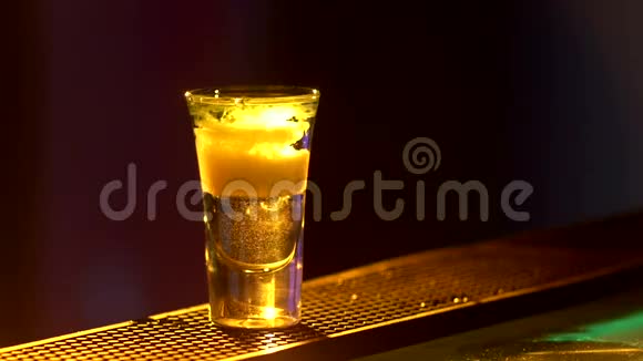 酒保正在制作鸡尾酒并添加绿色三种不同的液体在酒吧柜台的边缘拍摄关闭背部视频的预览图