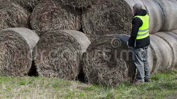 农民检查干草捆和谈论智能手机视频的预览图