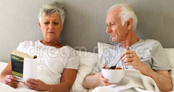 老人在床上一边吃早餐一边看书视频的预览图