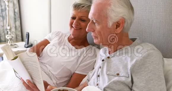 老人在床上一边吃早餐一边看书视频的预览图