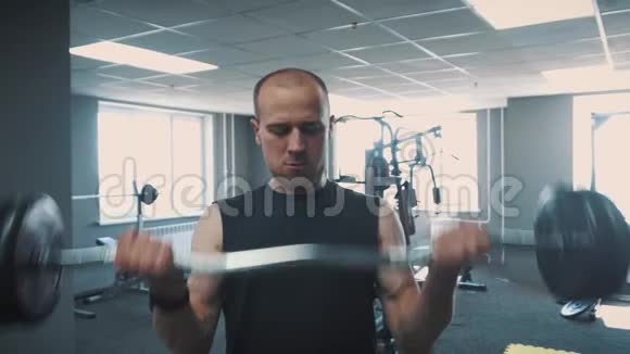 健身房里的哑铃肌肉训练那个人在健身房举起哑铃翻滚的大个子用哑铃训练视频的预览图
