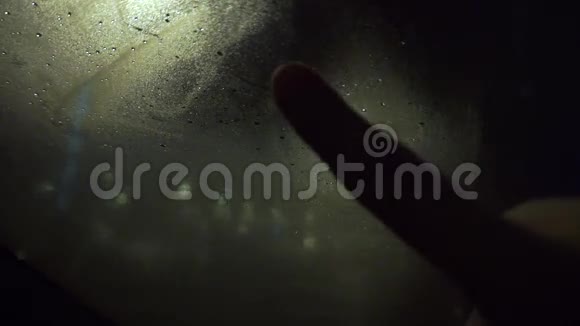 一个人在雾蒙蒙的窗户上对着暴风雨的夜晚视频的预览图