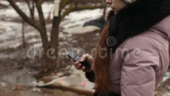 女孩在户外写冬季服装短信视频的预览图
