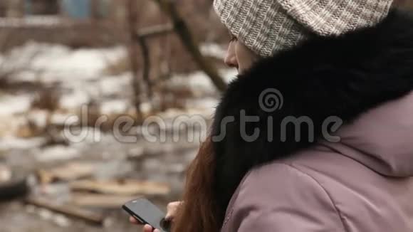 女孩在户外写冬季服装短信视频的预览图