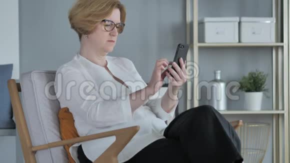 老年妇女在智能电话上浏览使用互联网视频的预览图