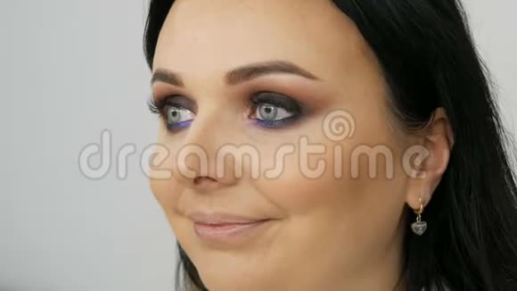 造型师化妆师用一种特殊的刷子在年轻的蓝色美女的脸上涂上粉底视频的预览图