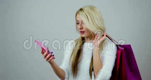 有趣的时尚女孩在手机上接听电话手里拿着购物包视频的预览图