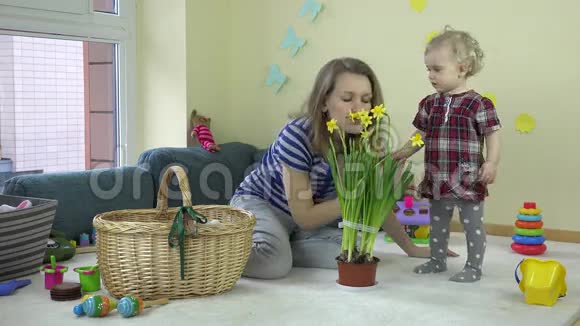 母亲带着宝贝女儿女孩闻着水仙花在锅里生长视频的预览图