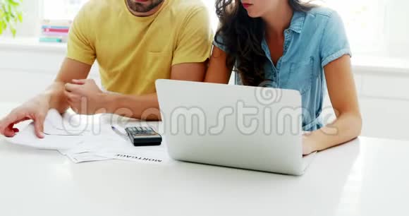 担心的夫妇在厨房里用笔记本电脑计算账单视频的预览图