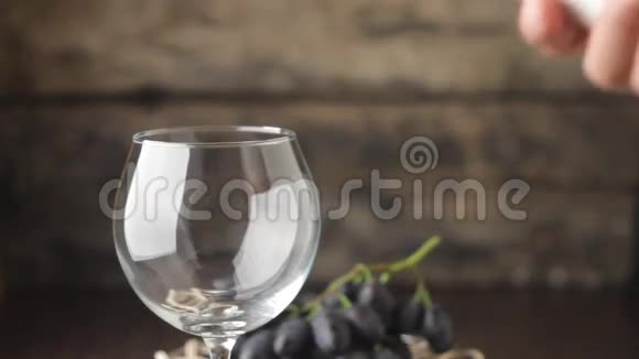 将葡萄酒倒入木质背景上的酒杯中视频的预览图