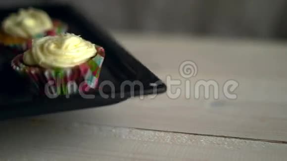 厨师把纸杯蛋糕托盘放在白色桌子上带白色奶油的松饼视频的预览图