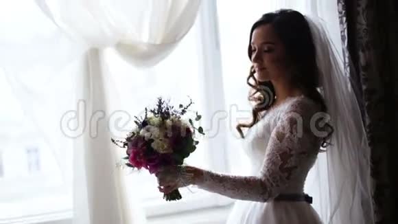 一位美丽的新娘左手捧着新娘的花束闻着花香视频的预览图