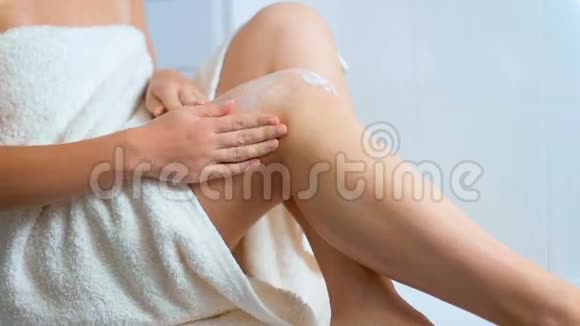 女青年洗澡后往腿上涂保湿乳液的特写镜头视频的预览图