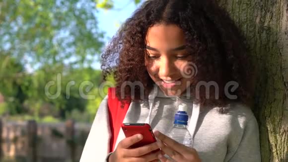 一个非洲裔美国少女用手机靠在树上视频的预览图