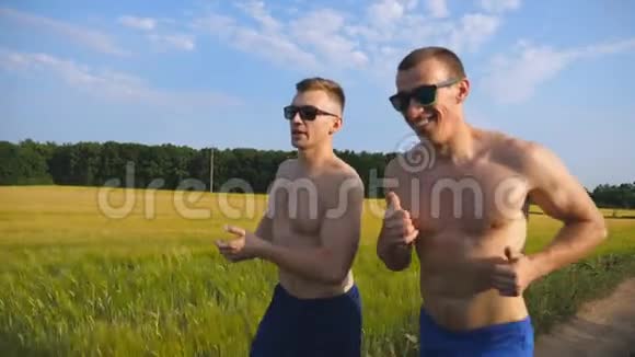 两个肌肉发达的男人在户外跑步和交谈年轻的运动员在球场上慢跑男运动员训练视频的预览图