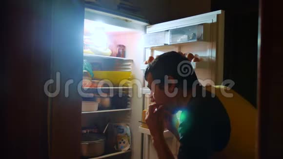 人们晚上从冰箱里吃饥饿和饕餮男人晚上看冰箱的生活方式饕餮视频的预览图