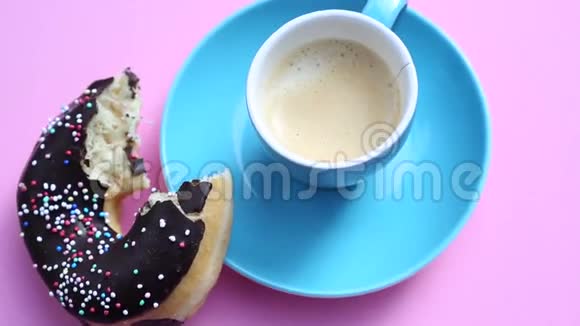蓝色咖啡杯旋转的粉红色盘子里有甜甜圈视频的预览图