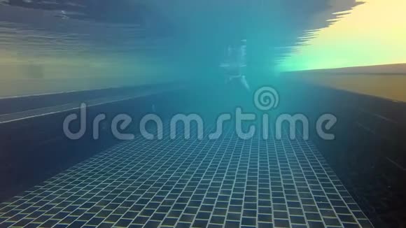 快乐开朗的年轻女子在一个蓝色的游泳套房游泳池水下景观操作摄像机视频的预览图