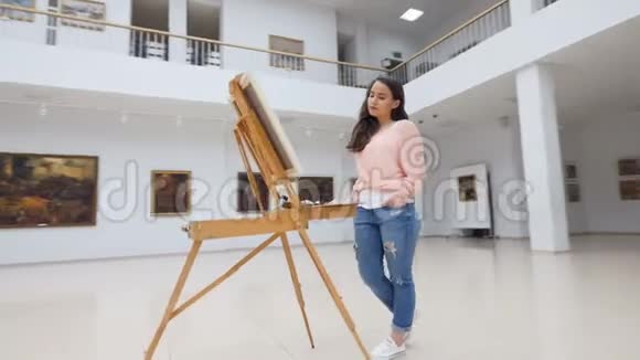 女孩站在美术馆空白画布前视频的预览图