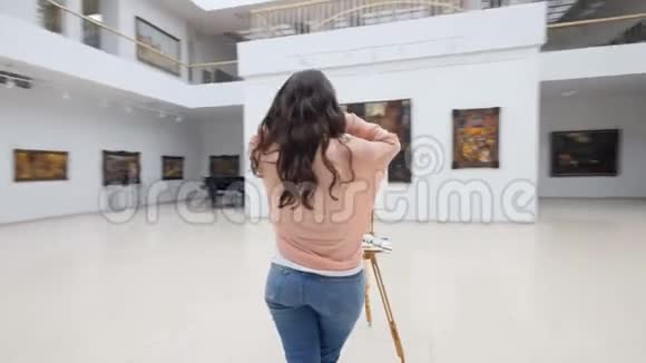图片画廊女孩站在空白画布前视频的预览图