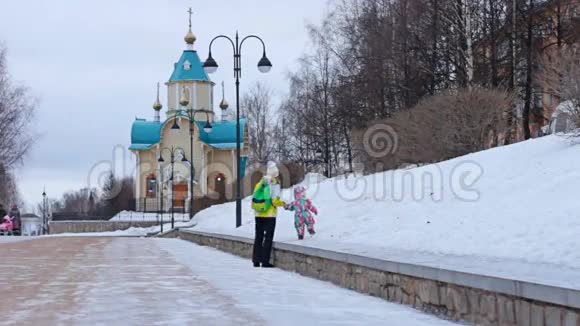 冬天一对母亲和一个孩子在俄罗斯教堂附近散步视频的预览图