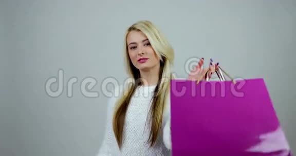 年轻的女人拿着购物包看着其中的一个表达出惊讶和幸福视频的预览图