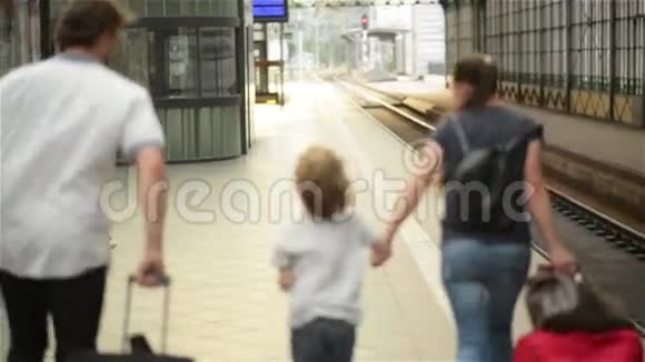 年轻的一家人有两个配偶一个儿子另一个女儿在火车离开火车站之前跑步去赶火车视频的预览图
