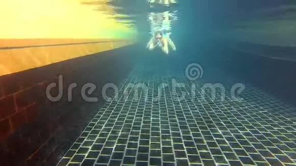 快乐开朗的年轻女子在蓝色游泳套房游泳池水下景观操作摄像机视频的预览图