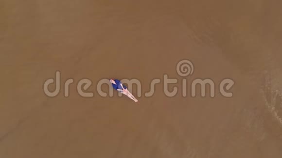 空中穿着蓝色鲜艳服装的年轻女子浅水区风景波罗的海的黄色日落景观Drone视频的预览图