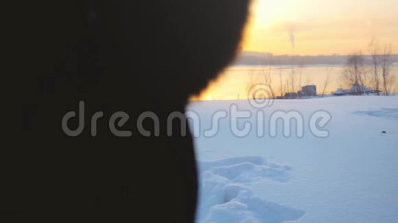 在美丽的夕阳下徒步旅行的女人穿过雪堆在冬天的雪地里缓慢地抛雪视频的预览图