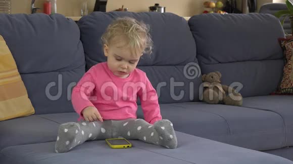 保姆帮助可爱的宝贝女孩使用智能手机坐在沙发上视频的预览图